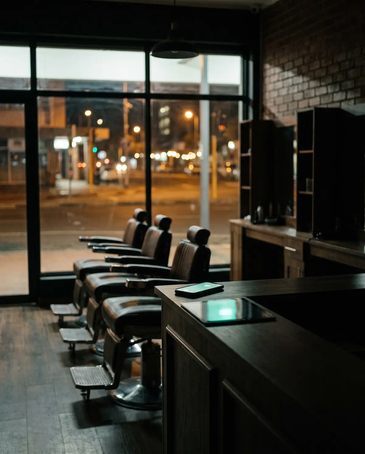 A salon after close — the reception phone glowing with an incoming booking